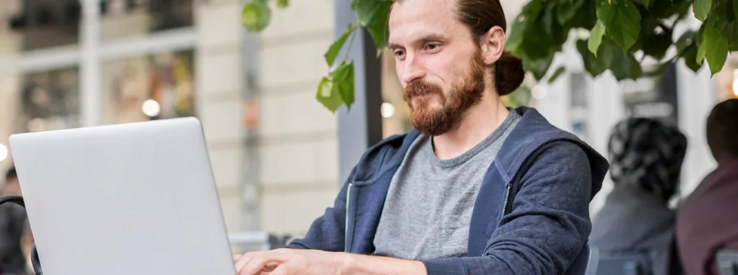 A trader working on a laptop at an outdoor cafe